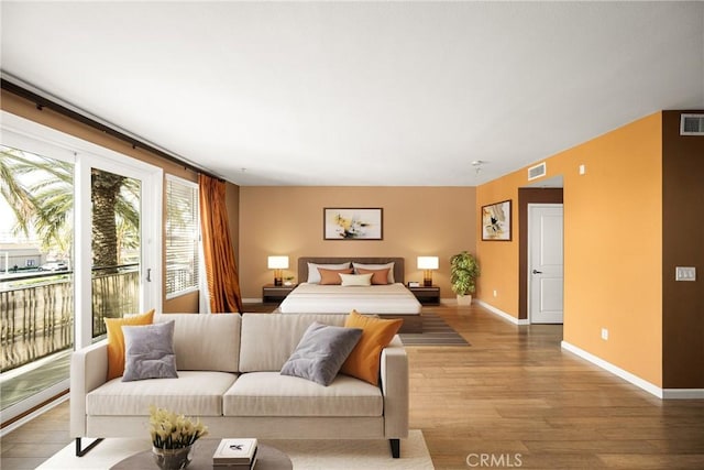 bedroom featuring access to exterior, visible vents, baseboards, and wood finished floors