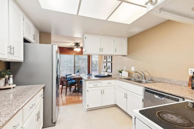 kitchen with appliances with stainless steel finishes, white cabinetry, sink, kitchen peninsula, and ceiling fan