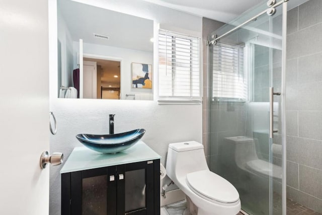 bathroom featuring toilet, a shower with shower door, and vanity