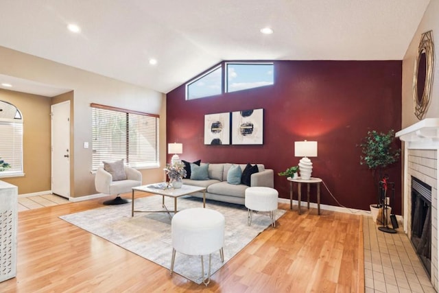 living room with a brick fireplace, light hardwood / wood-style floors, and vaulted ceiling