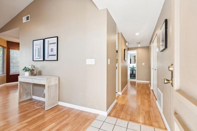 corridor featuring vaulted ceiling and light tile patterned flooring