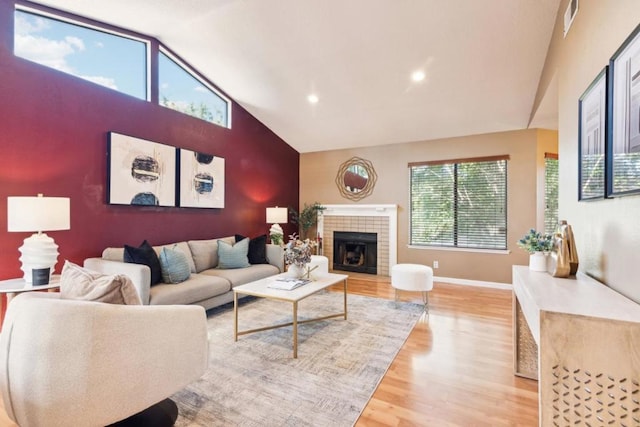 living room featuring lofted ceiling, light hardwood / wood-style floors, and a tile fireplace