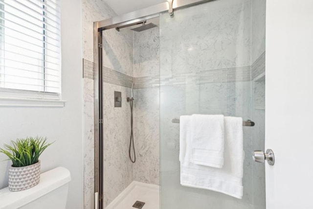 bathroom featuring toilet and a shower with door