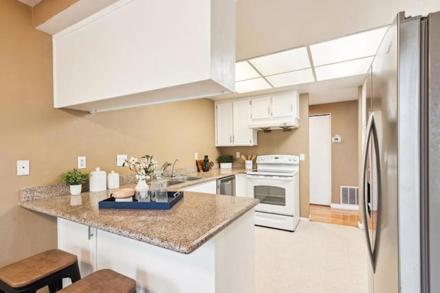 kitchen with kitchen peninsula, sink, stainless steel appliances, and a kitchen bar