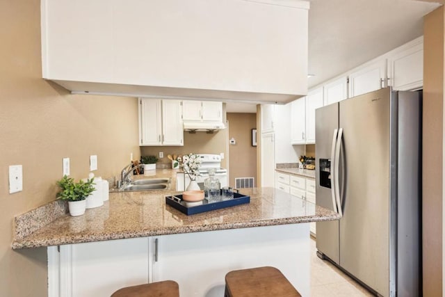 kitchen featuring kitchen peninsula, stainless steel refrigerator with ice dispenser, electric stove, a kitchen breakfast bar, and white cabinets