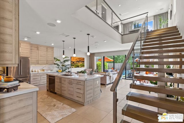 kitchen featuring an island with sink, stainless steel appliances, light brown cabinetry, and light tile patterned floors