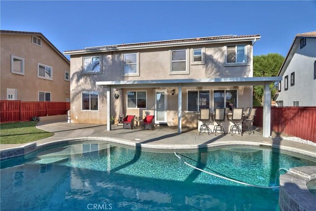 rear view of house with a fenced in pool and a patio area