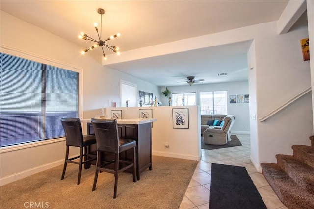 tiled dining space featuring ceiling fan with notable chandelier