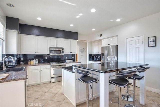 kitchen with white cabinets, a center island, sink, and stainless steel appliances