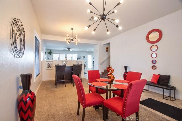 carpeted dining room with ceiling fan with notable chandelier