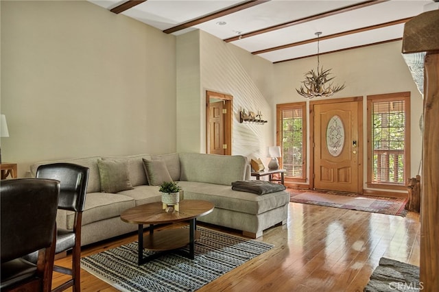 living room featuring a towering ceiling, hardwood / wood-style flooring, plenty of natural light, and beam ceiling