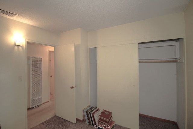 interior space with carpet floors, a textured ceiling, and a closet