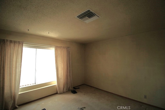 carpeted spare room with a textured ceiling