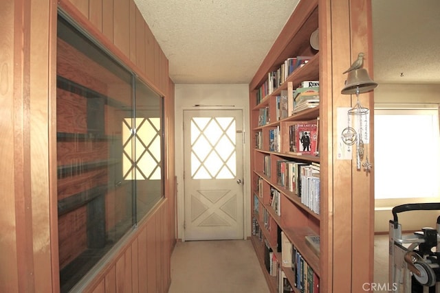 doorway with light colored carpet and a textured ceiling