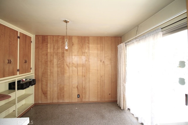 carpeted spare room featuring wooden walls