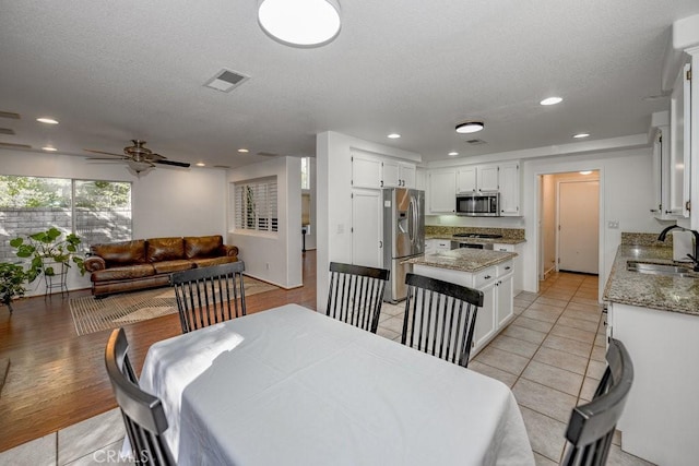 dining space with a textured ceiling, light hardwood / wood-style flooring, ceiling fan, and sink