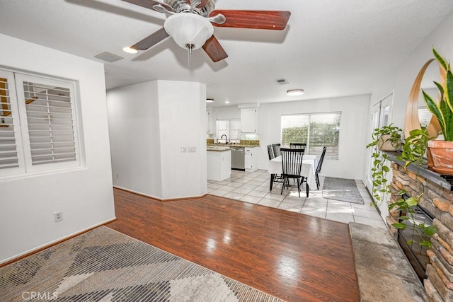 living area with baseboards, light wood-style flooring, visible vents, and ceiling fan