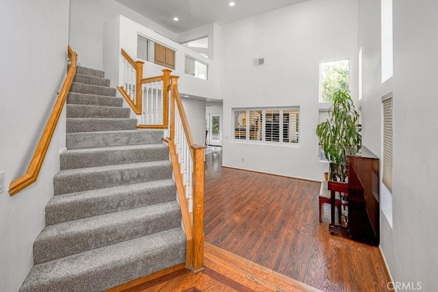 stairway featuring a high ceiling and wood-type flooring