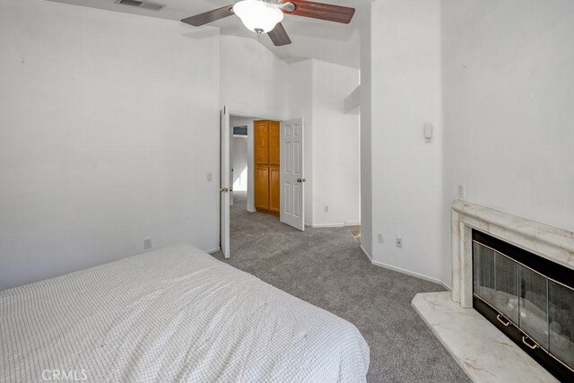 bedroom with a high end fireplace, ceiling fan, high vaulted ceiling, and light colored carpet