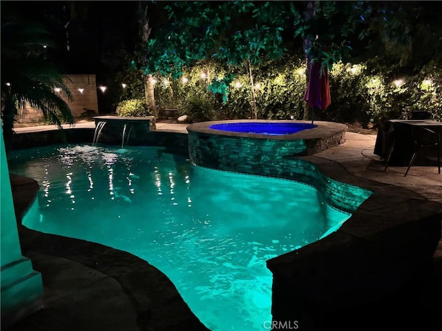 pool at twilight with a patio area and a pool with connected hot tub