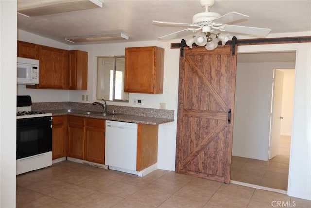 6052 Chia Ave Unit 29, Palms, CA 92277 - kitchen with a barn door, a sink, white appliances, brown cabinets, and light tile patterned flooring