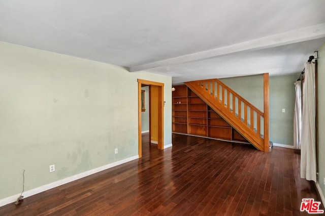 empty room featuring beam ceiling and dark wood-type flooring