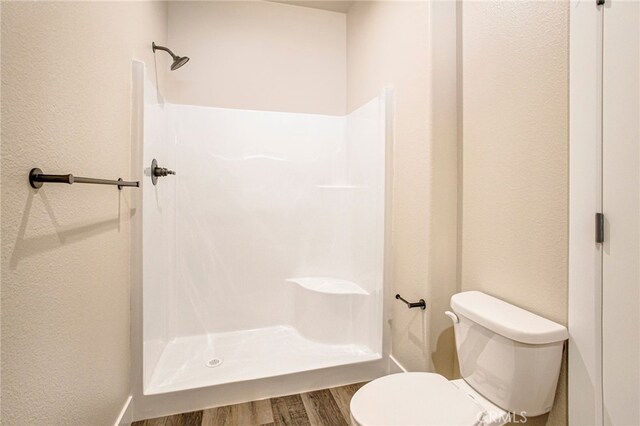 bathroom with a shower, toilet, and hardwood / wood-style flooring