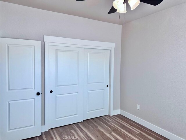 unfurnished bedroom featuring wood-type flooring, ceiling fan, and a closet