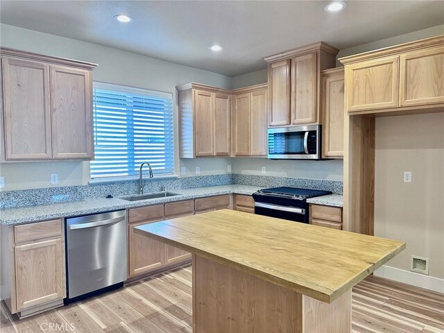 kitchen featuring light stone counters, light brown cabinets, sink, stainless steel appliances, and light hardwood / wood-style floors