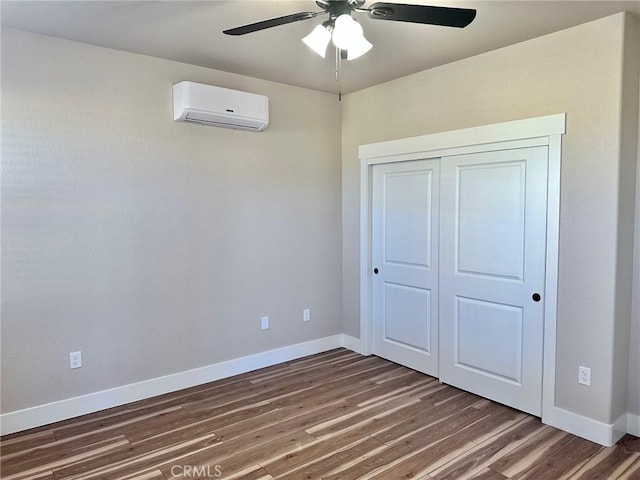 unfurnished bedroom featuring dark hardwood / wood-style flooring, a closet, ceiling fan, and a wall mounted air conditioner