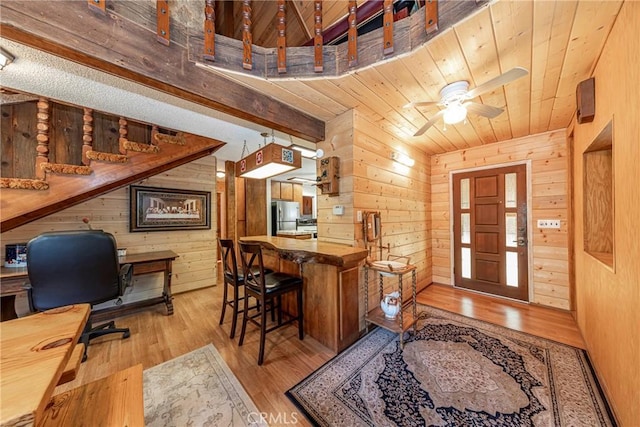 foyer entrance featuring light wood-type flooring, wood ceiling, ceiling fan, and wood walls