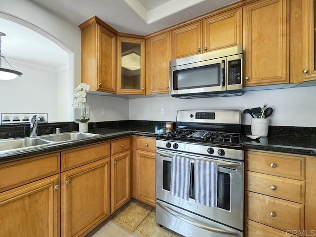 kitchen featuring dark stone countertops, appliances with stainless steel finishes, sink, and light tile patterned floors