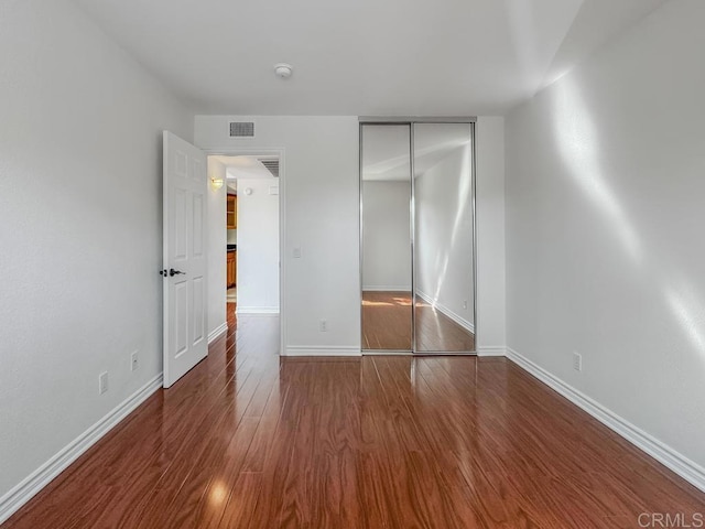 unfurnished bedroom featuring dark hardwood / wood-style flooring and a closet