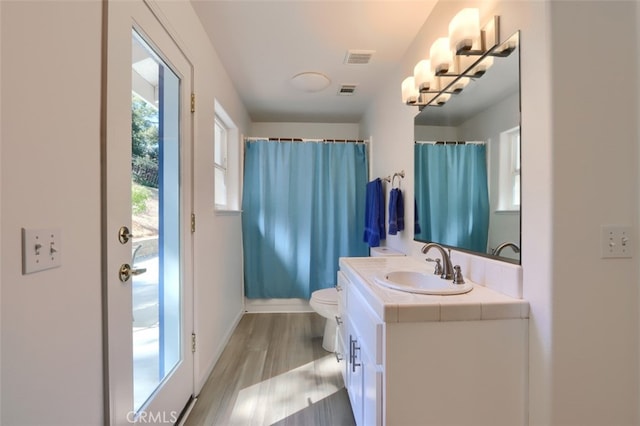 bathroom with a shower with shower curtain, hardwood / wood-style floors, vanity, and toilet