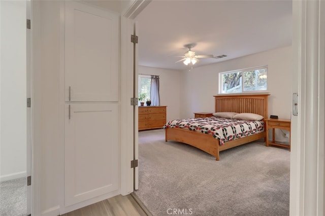 bedroom featuring multiple windows, light carpet, and ceiling fan