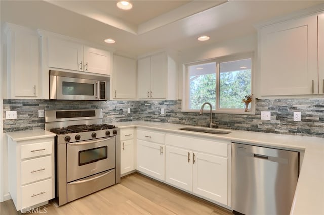 kitchen featuring appliances with stainless steel finishes, light wood-type flooring, white cabinetry, and sink