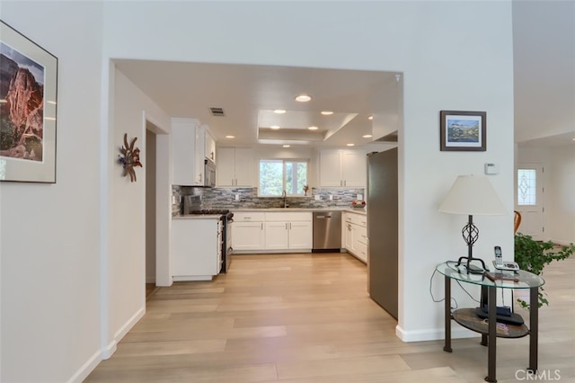 kitchen featuring a raised ceiling, white cabinetry, sink, and stainless steel appliances