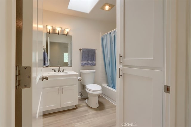 full bathroom with shower / bath combo, hardwood / wood-style flooring, a skylight, vanity, and toilet