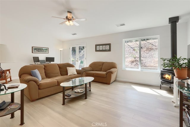 living room featuring light hardwood / wood-style flooring, a wood stove, and ceiling fan