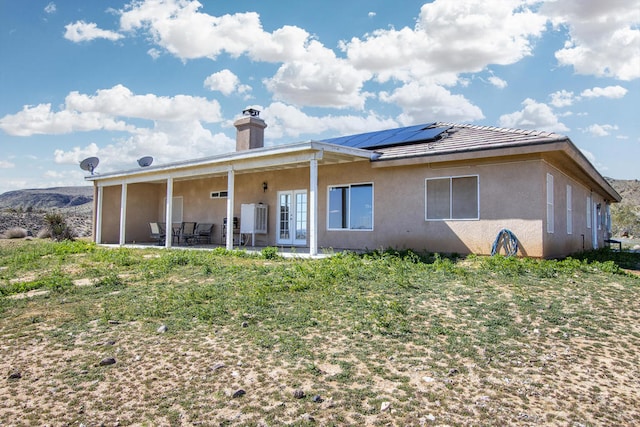 back of house with solar panels and a patio area