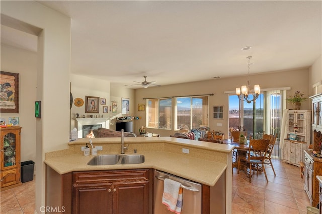 kitchen featuring dishwasher, sink, pendant lighting, light tile patterned floors, and ceiling fan with notable chandelier