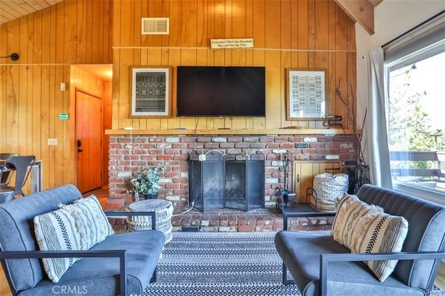 living room featuring lofted ceiling with beams, a brick fireplace, and wood walls