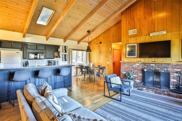 living room with wood ceiling, wood-type flooring, high vaulted ceiling, and a skylight