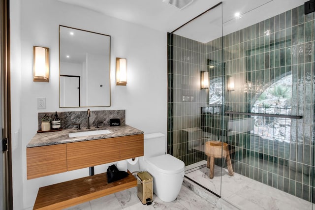 bathroom featuring vanity, tiled shower, and toilet