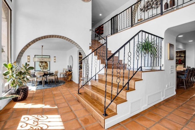 staircase with tile patterned flooring and a high ceiling