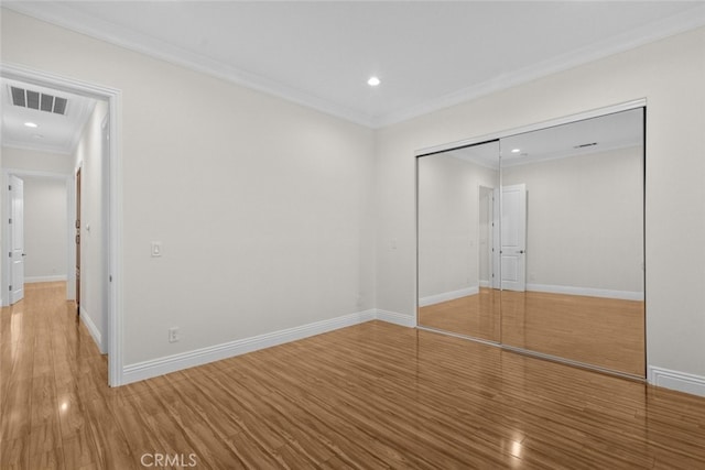 unfurnished bedroom with ornamental molding, a closet, and hardwood / wood-style floors