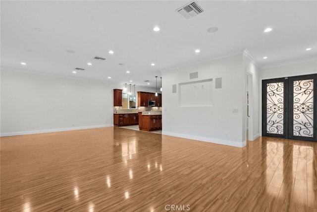 unfurnished living room with crown molding, light hardwood / wood-style flooring, and french doors