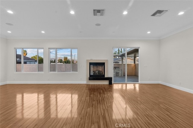 unfurnished living room featuring ornamental molding and light wood-type flooring