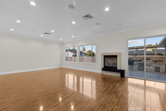 unfurnished living room featuring ornamental molding and light hardwood / wood-style flooring