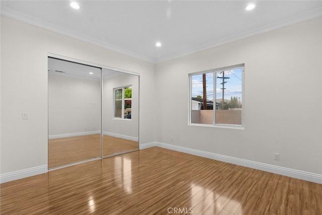 unfurnished bedroom featuring hardwood / wood-style flooring, a closet, and crown molding